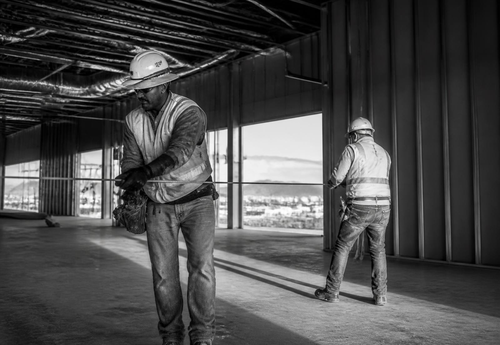 Two electricians laying out work inside a partially framed Phoenix commercial building